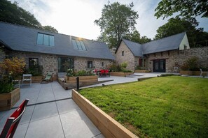 Ein Steinhaus mit Terrasse, Sitzgelegenheit im Freien und einem Rasen.