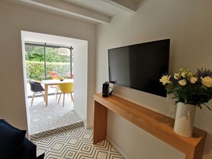 A modern living room with a flat-screen TV mounted on a wooden console, a vase with yellow flowers, and a patterned floor. - Le Sant C'hireg    . (Concarneau)