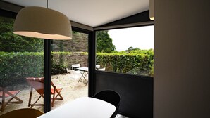 Un'area pranzo moderna con tavolo e sedie, ampie finestre e vista su un giardino.