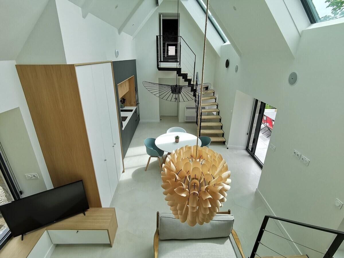 A modern interior with a dining area, a staircase, and a unique ceiling light fixture.