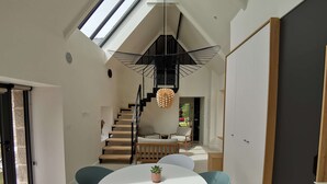 A modern interior with a skylight, a spiral staircase, a round dining table, and a minimalist decor. - L'Etoile du Roy    . (Concarneau)