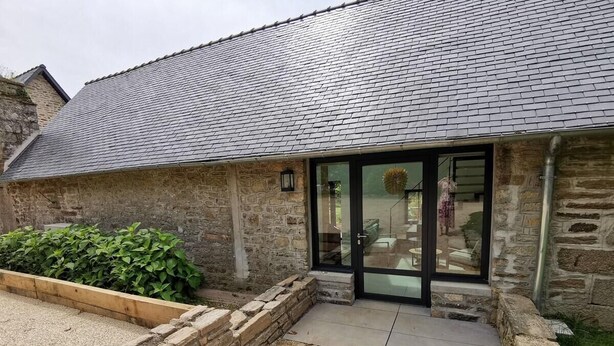 A stone building with a tiled roof, a wooden planter with green plants, and a gravel driveway. - L'Etoile du Roy    . (Concarneau)