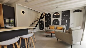 Ein zeitgemäßer Wohnraum mit Küchenbereich, einer Couch und einer Treppe.