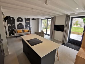 A modern living room with a large central table, a sofa, and a television.