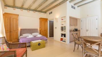 A bedroom with a bed, wooden wardrobe, and a small table with chairs.
