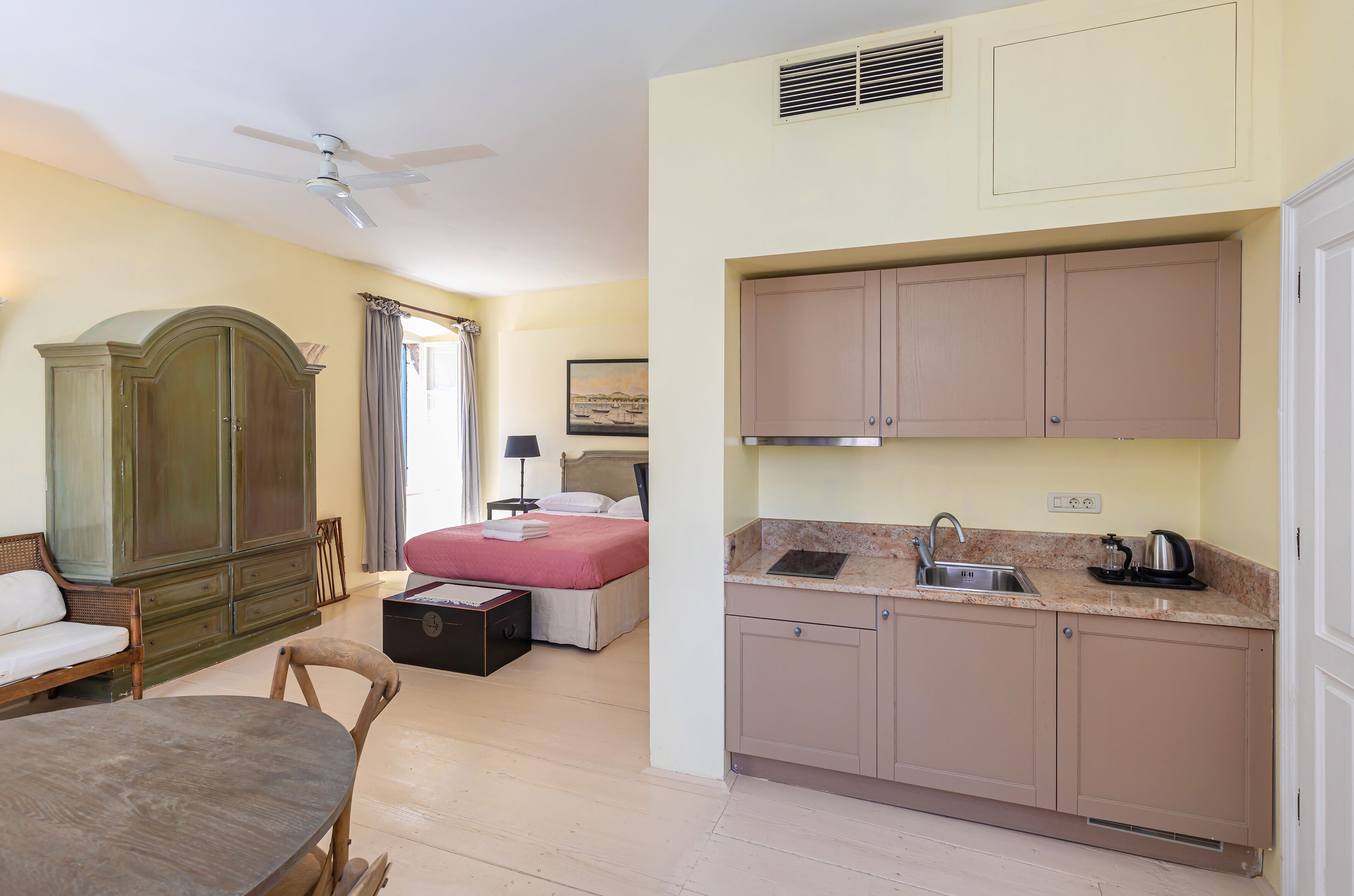 Ein Hotelzimmer mit Bett, Esstisch, Küchenzeile und großem Kleiderschrank.