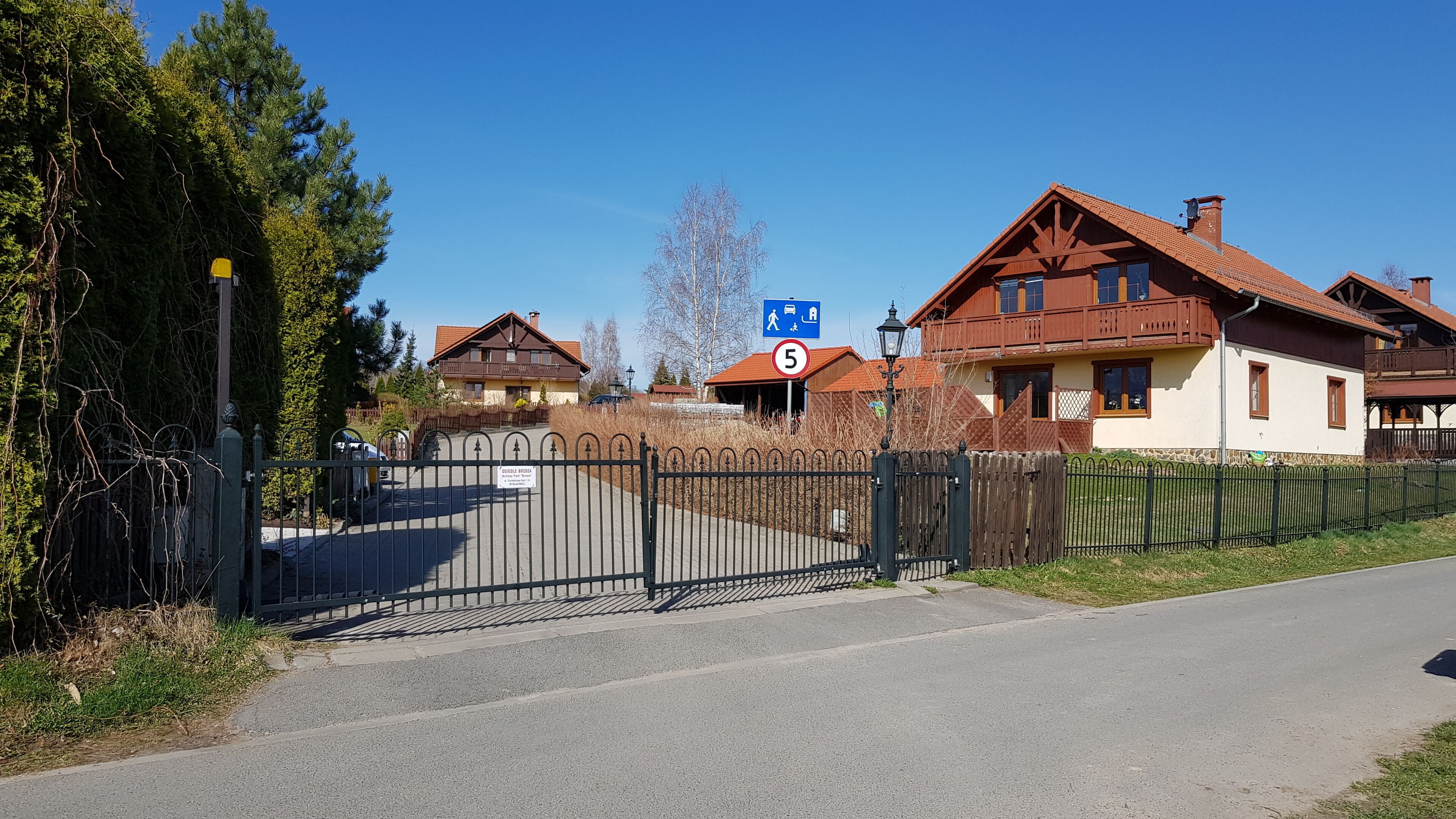 Et boligområde med huse, en låst port og en klar himmel.