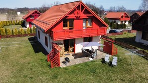 A red two-story house with a balcony, a patio with outdoor furniture, and a well-maintained lawn. - Villa Leika - for families with a view of the Schneekoppe, dogs allowed (Mysłakowice)