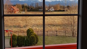 A view from a window with a red balcony railing, overlooking a rural landscape with fields, trees, and distant mountains. - Villa Leika - for families with a view of the Schneekoppe, dogs allowed (Mysłakowice)