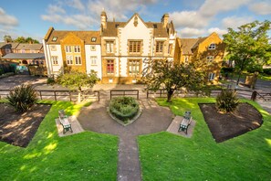 A traditional building with a symmetrical facade, a central entrance, and a well-maintained garden with benches. - Inviting 1-bed Apartment in Banbury (Banbury)