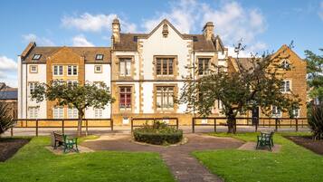 A historic building with a symmetrical facade, multiple windows, and a central garden area with benches.