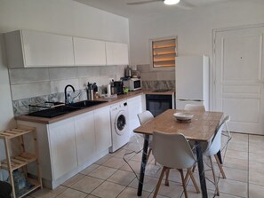 A compact kitchen with a washing machine, a sink, and a dining area with chairs. - T2 Anse à l'Ane, a 5-minute walk from the beach (Les Trois-Îlets)