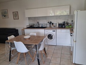 A compact kitchen with a washing machine, a sink, and a dining area with a table and chairs. - T2 Anse à l'Ane, a 5-minute walk from the beach (Les Trois-Îlets)