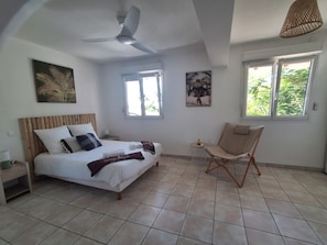 A bedroom with a bed, a chair, a ceiling fan, and two windows. - T2 Anse à l'Ane, a 5-minute walk from the beach (Les Trois-Îlets)