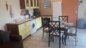 Eine kompakte Küche mit Waschmaschine, einem Esstisch mit Stühlen und einer kleinen Sitzecke mit einer Couch.