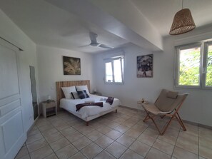 Ein Schlafzimmer mit einem Bett, einem Deckenventilator, einem Fenster und einem Stuhl.