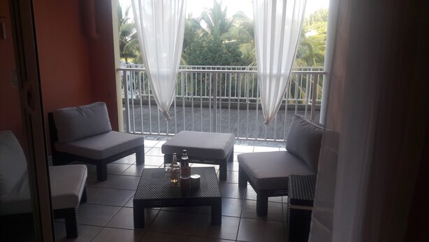Ein Balkon mit einer Couch, einem kleinen Tisch und einem Stuhl.