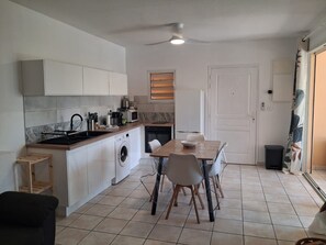 A compact kitchen with a dining area, a washing machine, and a ceiling fan.