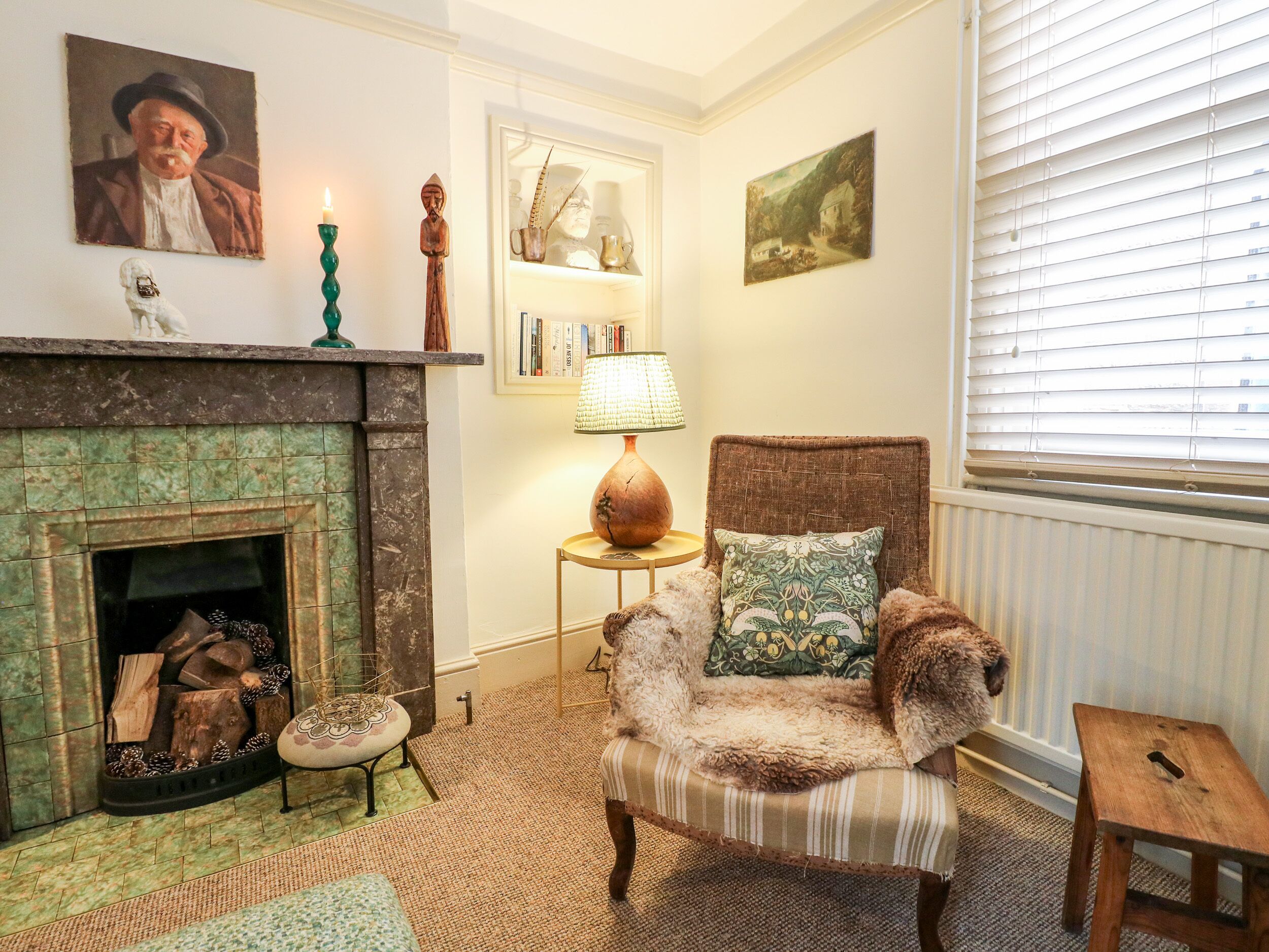 A cozy room with a fireplace, a chair with a cushion, a small table, and a bookshelf.