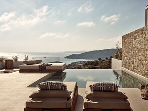 Un espace aménagé au bord de la piscine, avec des chaises longues et une vue sur la mer.
