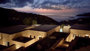 A stone building with multiple terraces and a pool, overlooking a coastal landscape at dusk. - The Sall Suites Complex A - Sea Views (Zakynthos)
