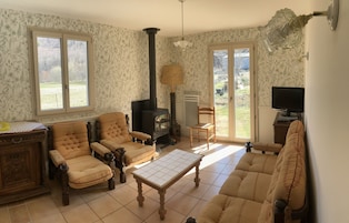 A cozy living room with a fireplace, two armchairs, a sofa, and a television.