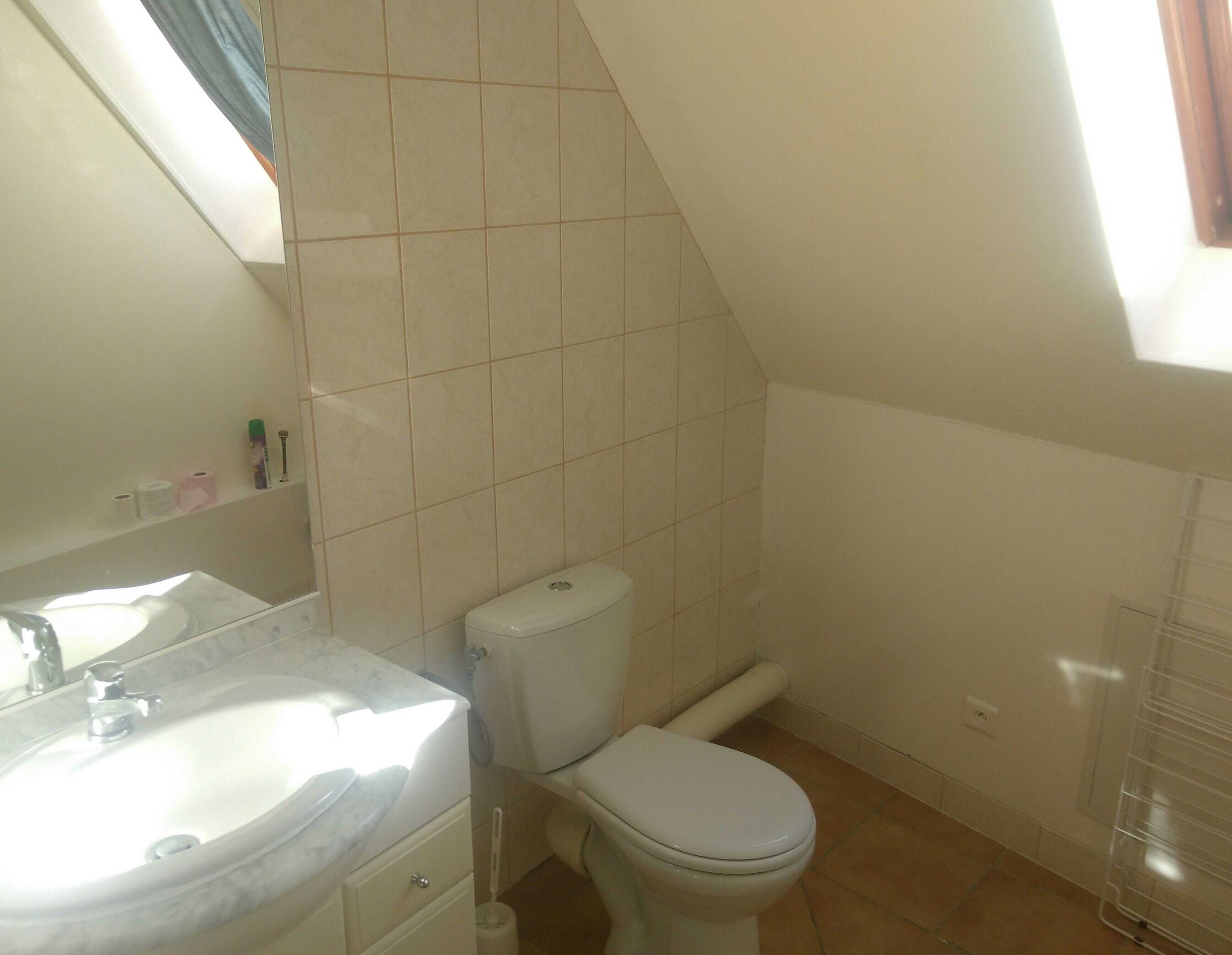 A bathroom with a white sink, toilet, and tiled walls.