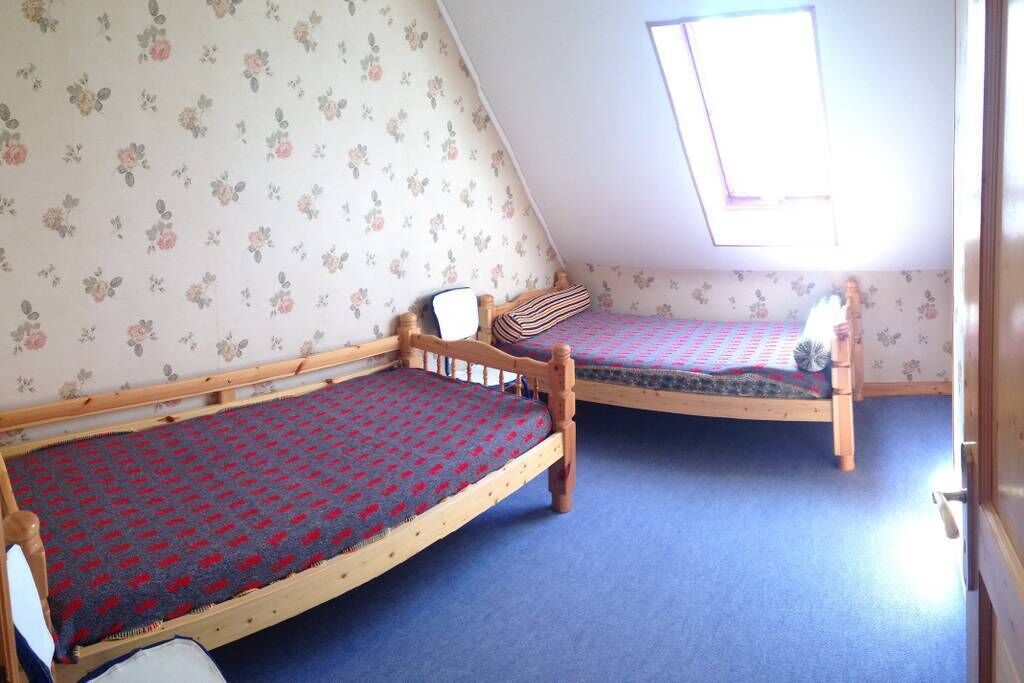 Una stanza con due letti di legno, un soffitto spiovente e un lucernario.