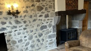 Un salón acogedor con pared de piedra, chimenea, sofá y mesa de centro.