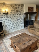 Un salón acogedor con pared de piedra, chimenea, sofá y mesa de centro.