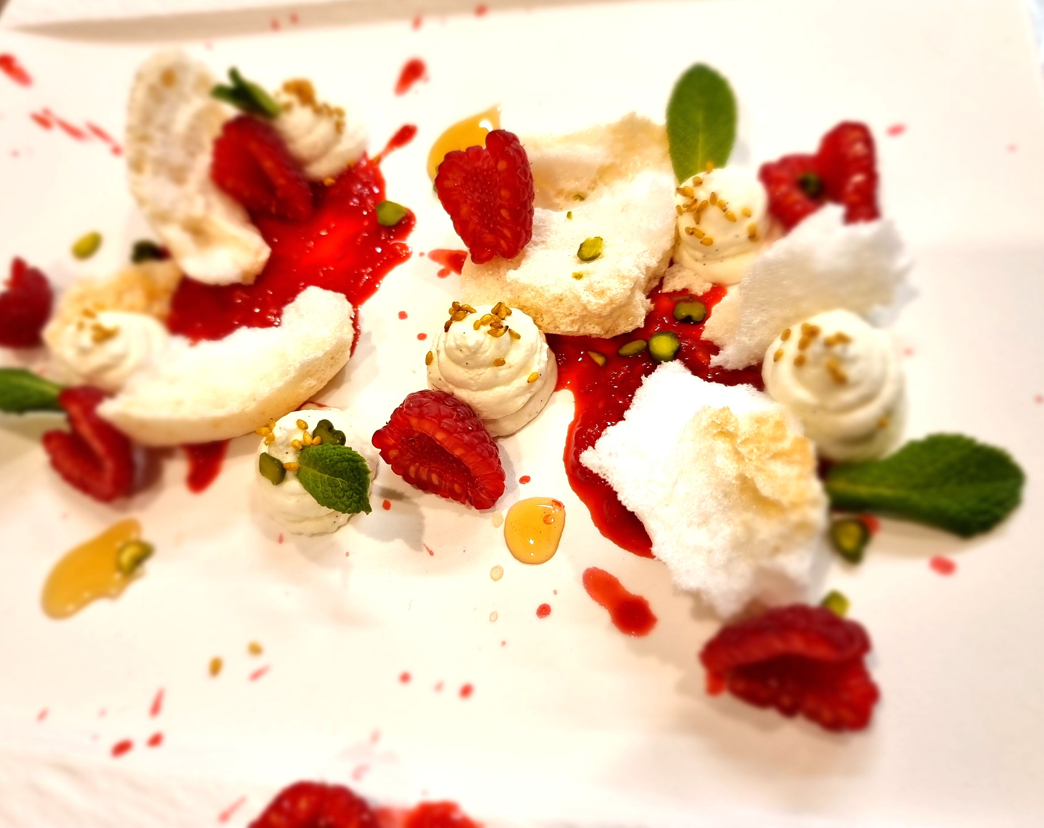 A dessert plate with various fruits, whipped cream, and a white base, likely a panna cotta or similar dessert.