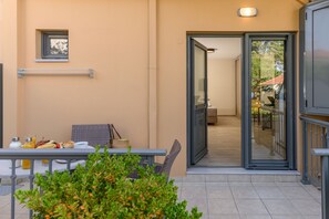 A balcony with a table set for breakfast, a wicker chair, and a small window.
