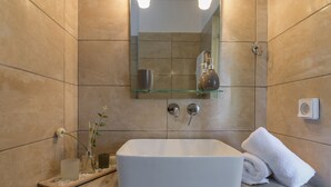 Ein Badezimmer mit einem rechteckigen weißen Waschbecken, einer Glasablage darüber und einem Handtuch auf der Ablagefläche.