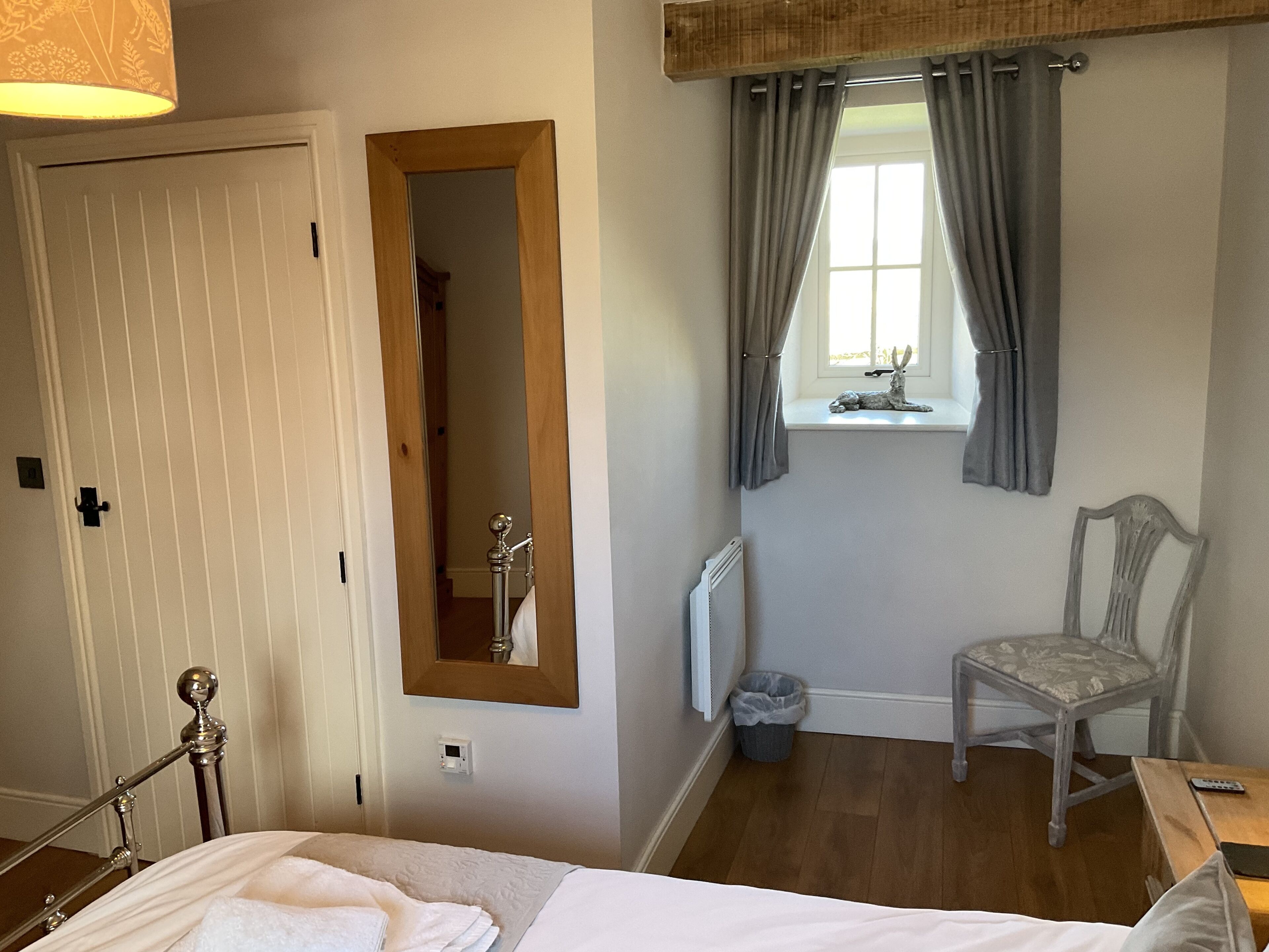 Ein Schlafzimmer mit Bett, Stuhl, einem Fenster mit Vorhängen, einer Heizung und einer Tür.