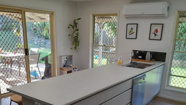 A modern kitchen with a large island, a sink, and a window overlooking a garden. - Spacious Family house in great location. (Tanah Merah)