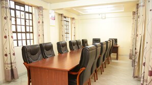A conference room with a long wooden table and multiple chairs. - Roza Guests House (Naivasha)