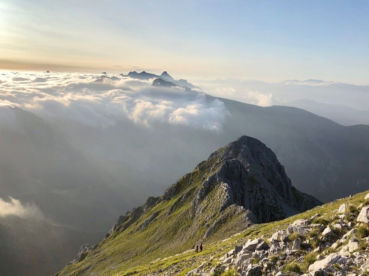 Un paysage de montagne avec un sommet proéminent au premier plan et une chaîne de montagnes en arrière-plan.