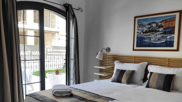Una habitación de hotel con una cama, un cuadro, una ventana con cortinas y un equipo de aire acondicionado.