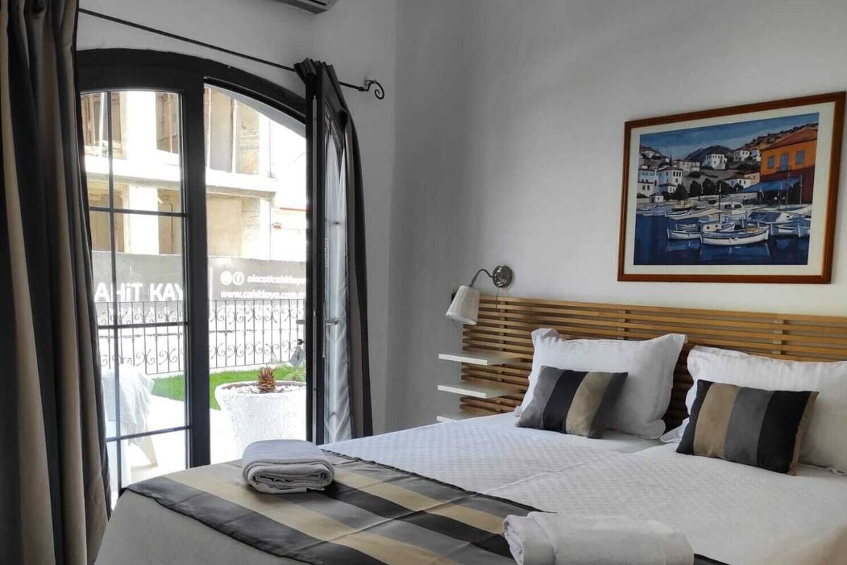 Quarto de hotel com uma cama, um quadro, uma janela com cortinas e um ar condicionado.