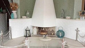 Un vestíbulo con chimenea central, un tapete estampado y una escalera que sube a un nivel superior.