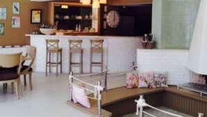 Un interior moderno con zona de cocina, bar, asientos y una pared decorativa.