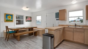 A modern kitchen with wooden cabinets, a stainless steel sink, and a built-in bench.
