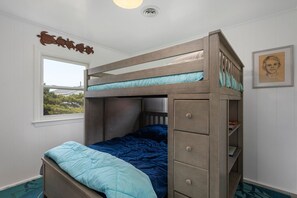 Uma cama beliche com gavetas na cabeceira, uma janela com vista e um quadro na parede.