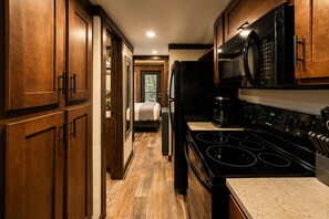 A kitchen with wooden cabinets, a stove, a microwave, and a refrigerator.