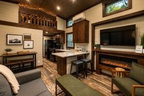 Un área de estar acogedora con chimenea, televisor y cocina con alacenas de madera.