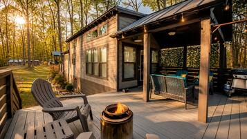 A wooden deck with outdoor furniture, a fire pit, and a covered seating area.