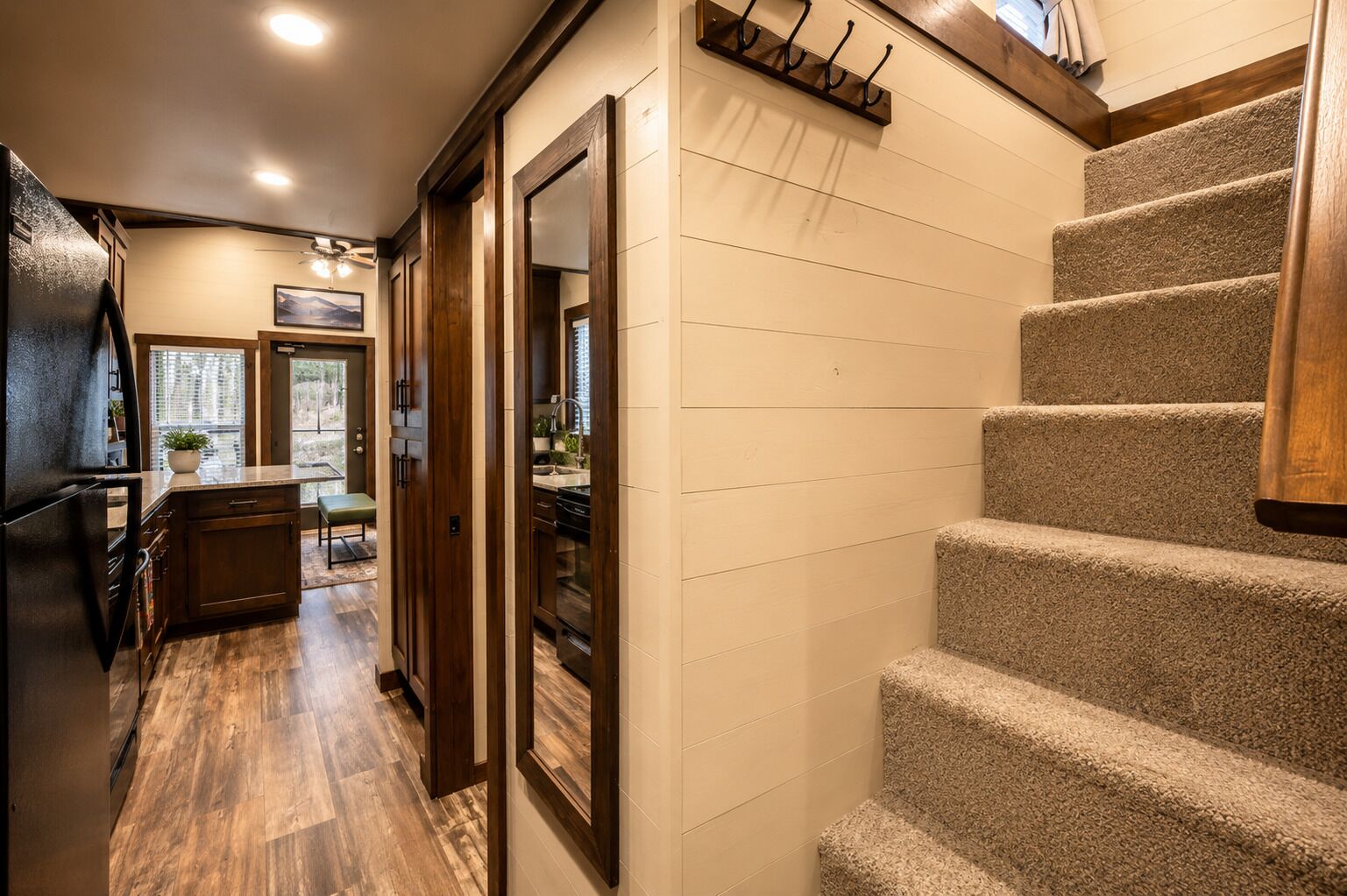 A kitchen with wooden cabinets, a refrigerator, and a dining area with a bench.