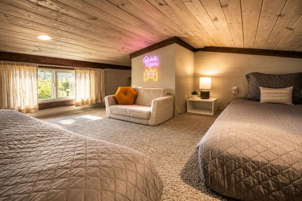 Habitación de hotel con dos camas, un sofá, un letrero de neón, una lámpara y una ventana con cortinas.