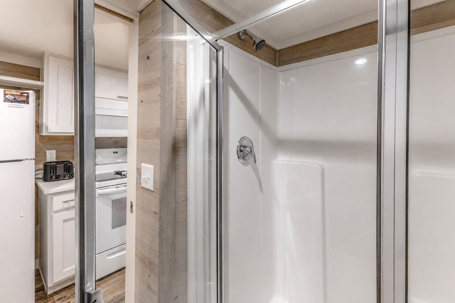 A modern bathroom with a glass shower enclosure, a white toilet, and a sink.