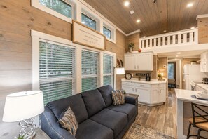 A modern interior with a dark sofa, a dining area, and a kitchen.